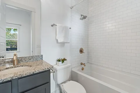 a bathroom with a granite countertop sink a toilet and shower