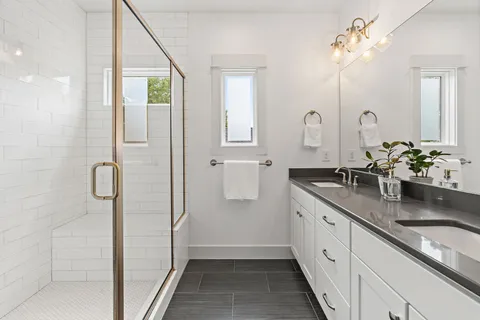 a bathroom with a double vanity sink mirror and shower