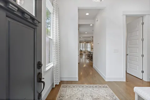 a view of a hallway with wooden floor and a livingroom