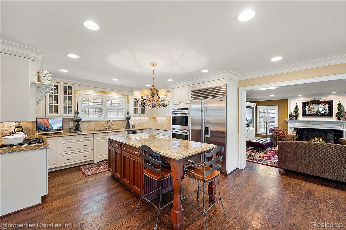 135 Clifton Road Bloomfield Hills, MI 48301 - Photo 19 of 77 Gourmet kitchen featuring a substantial central island with seating, granite countertops, and wood-finish flooring