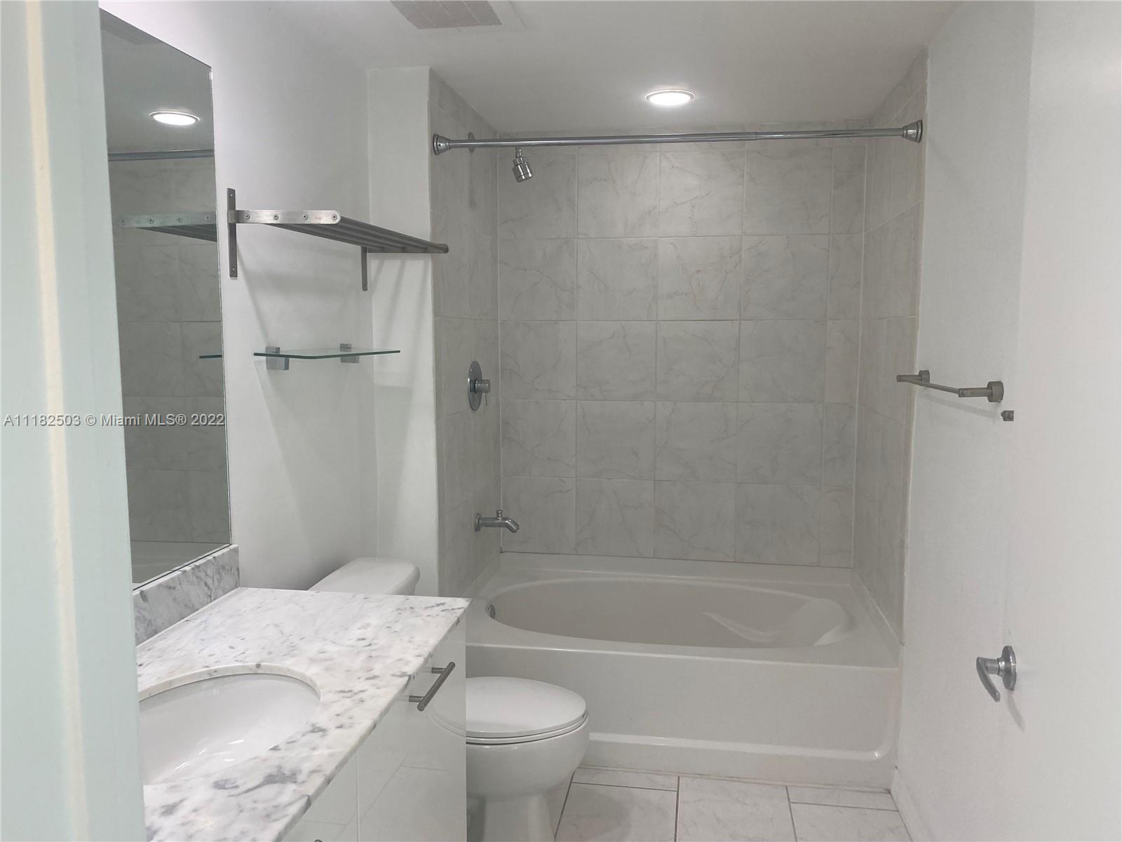 950 Brickell Bay Drive, Unit 602 Miami, FL 33131 - Photo 13 of 16 a bathroom with a granite countertop bathtub shower sink vanity and toilet