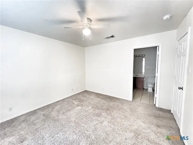 an empty room with a ceiling fan and carpet
