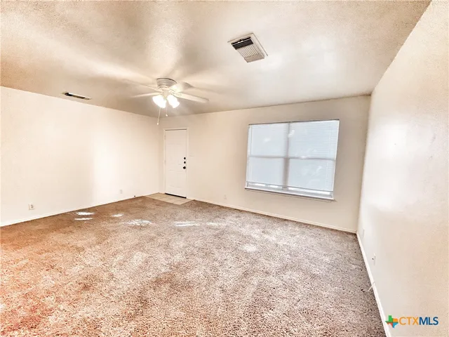 en empty room with windows and ceiling fan