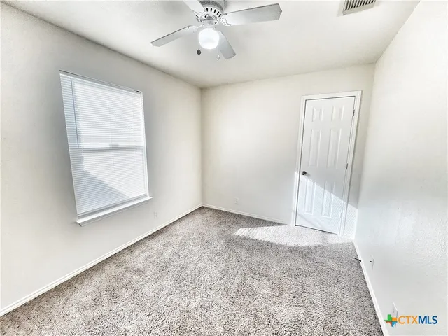 an empty room with a window and a ceiling fan