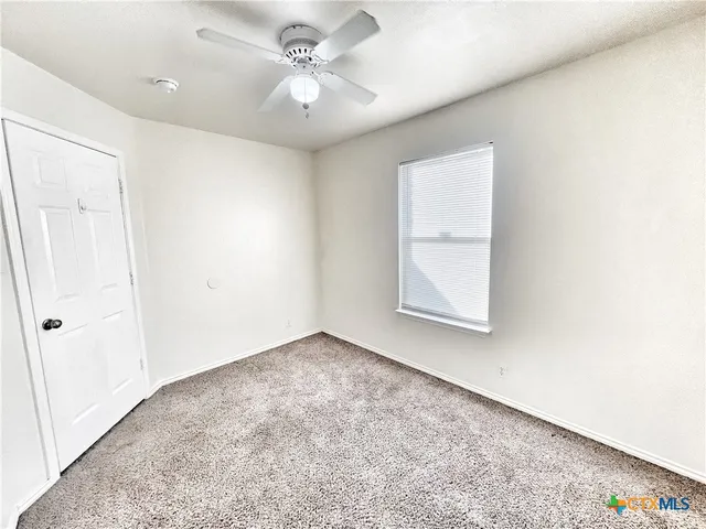 an empty room with a window and a ceiling fan