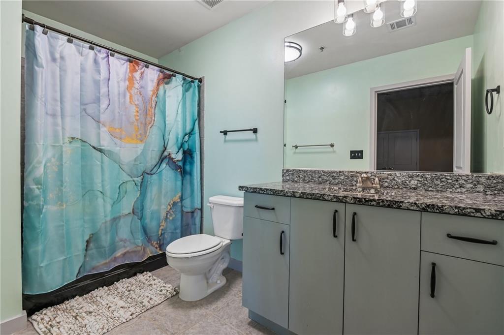 250 Pharr Road Northeast, Unit 701 Atlanta, GA 30305 - Photo 11 of 21 a bathroom with a granite countertop sink a toilet a mirror and shower