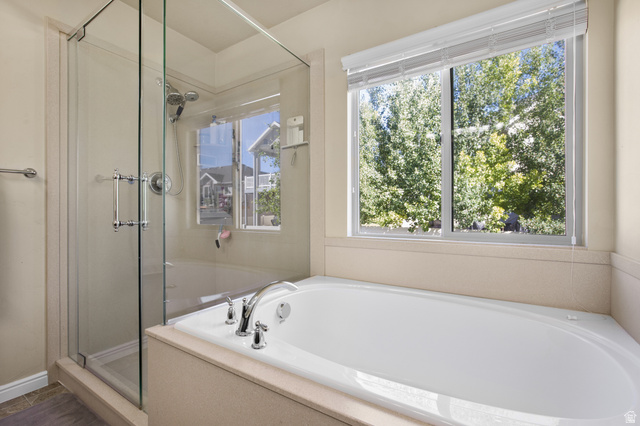 2005 Redtail Way Layton, UT 84040 - Photo 23 of 37 Built-in soaking tub with chrome fixtures, glass-enclosed shower with a handheld showerhead, and a large window providing natural light