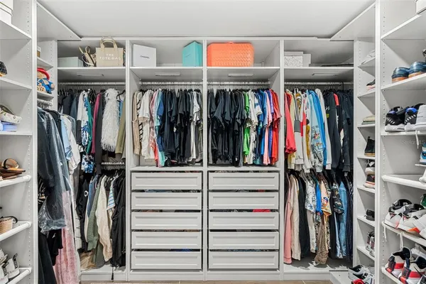 a view of walk in closet with clothes and shoes