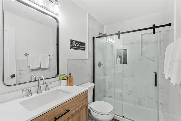 a bathroom with a sink toilet a mirror and shower