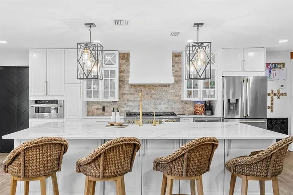 a kitchen with stainless steel appliances granite countertop a table chairs and microwave