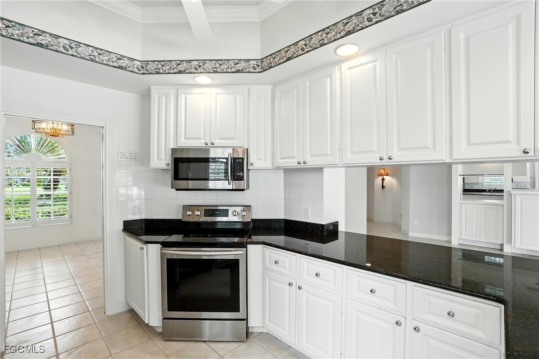4017 Isla Ciudad Court Naples, FL 34109 - Photo 10 of 36 a kitchen with granite countertop white cabinets and black appliances