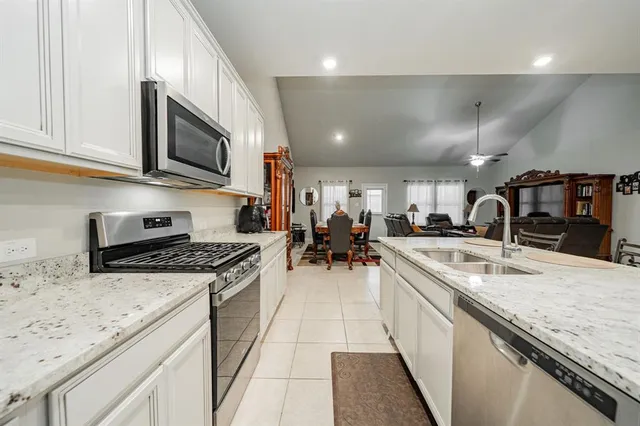 a large kitchen with stainless steel appliances granite countertop a lot of counter space and wooden floor