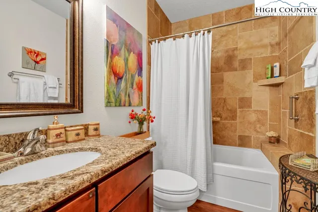a bathroom with a granite countertop sink a toilet and a bathtub