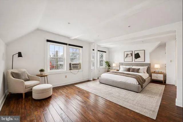 a spacious bedroom with a bed and wooden floor