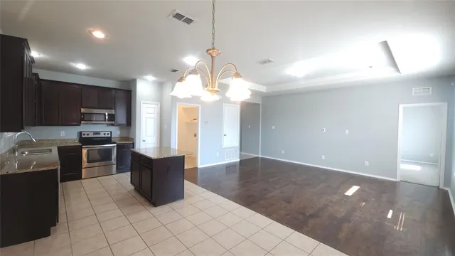 a kitchen with stainless steel appliances granite countertop wooden cabinets a stove top oven a sink and dishwasher