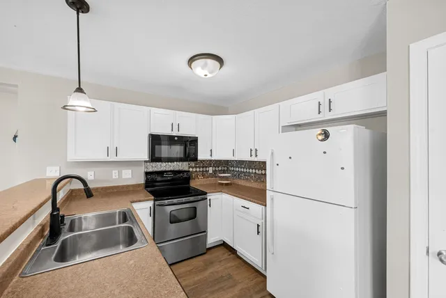 a kitchen with stainless steel appliances granite countertop a refrigerator a sink a stove and white cabinets