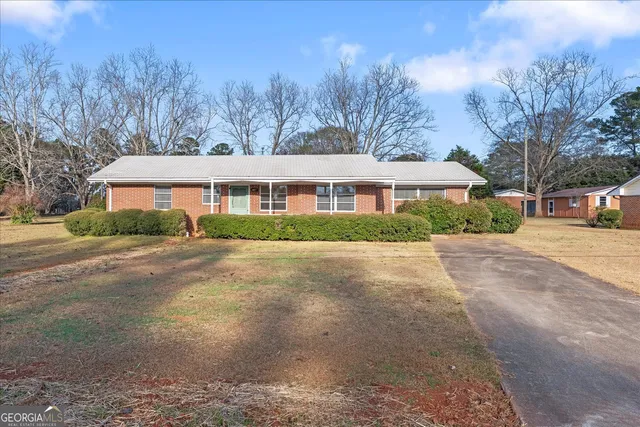 a view of house with yard and trees in the background