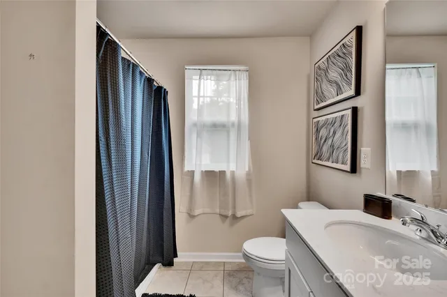 a bathroom with a granite countertop sink a toilet a mirror and shower