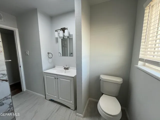 a bathroom with a toilet a sink a window and mirror