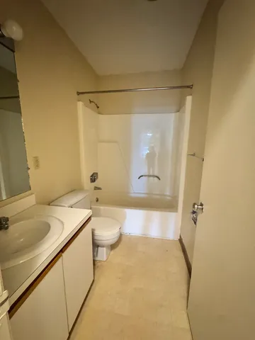 a bathroom with a granite countertop sink a toilet and shower
