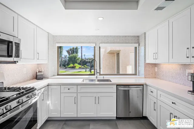 a kitchen with white cabinets and window