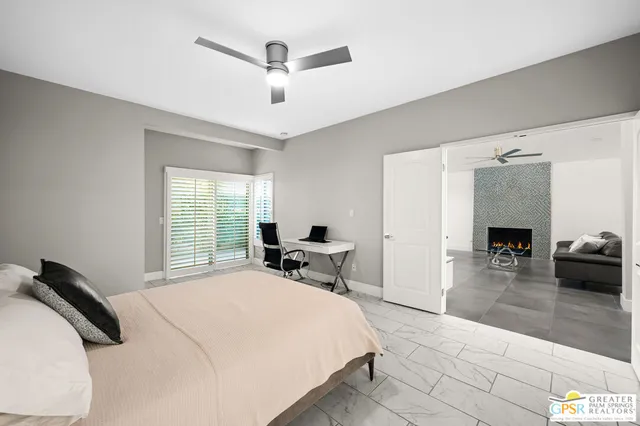 a bedroom with a bed a chair and potted plants with the wooden floor