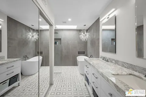 a bathroom with a granite countertop double vanity sink a mirror and a bathtub