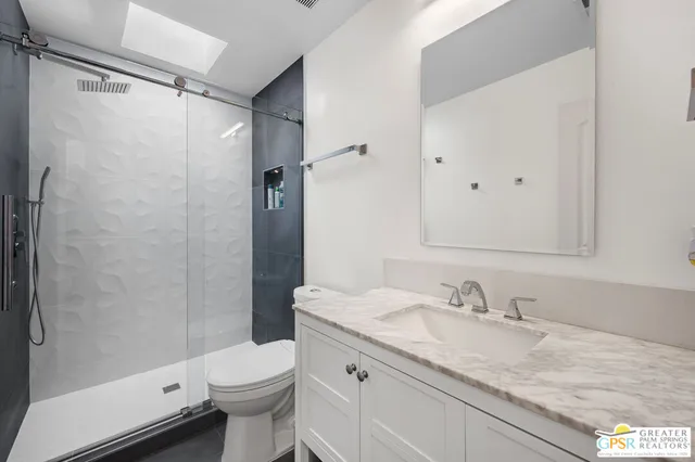 a bathroom with a granite countertop sink toilet and shower
