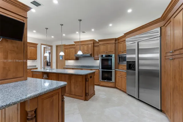 a kitchen with stainless steel appliances kitchen island granite countertop a sink a refrigerator and chairs