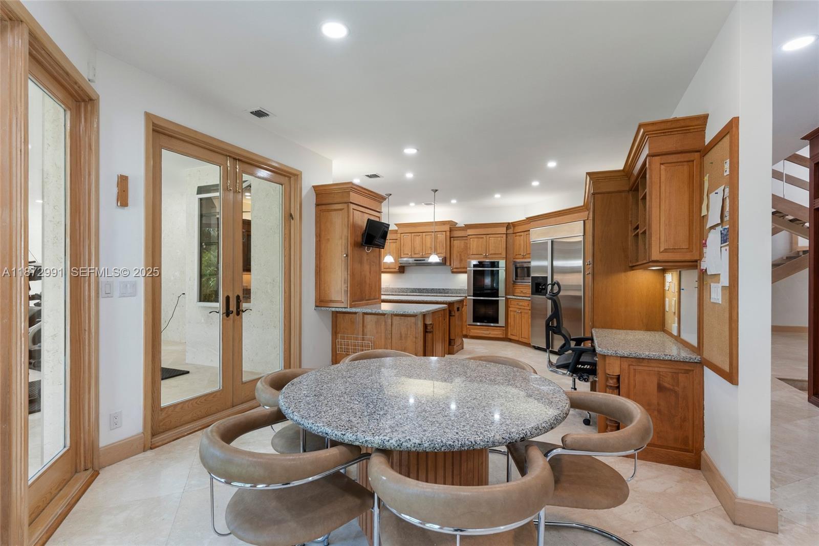 6190 Southwest 102nd Street Pinecrest, FL 33156 - Photo 25 of 52 a kitchen with stainless steel appliances kitchen island granite countertop a sink a refrigerator and chairs