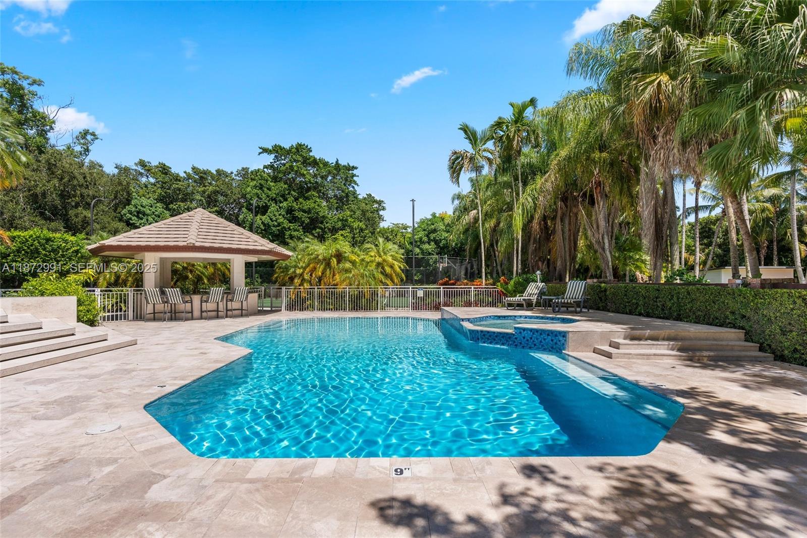 6190 Southwest 102nd Street Pinecrest, FL 33156 - Photo 41 of 52 a view of a swimming pool with lawn chairs under an umbrella