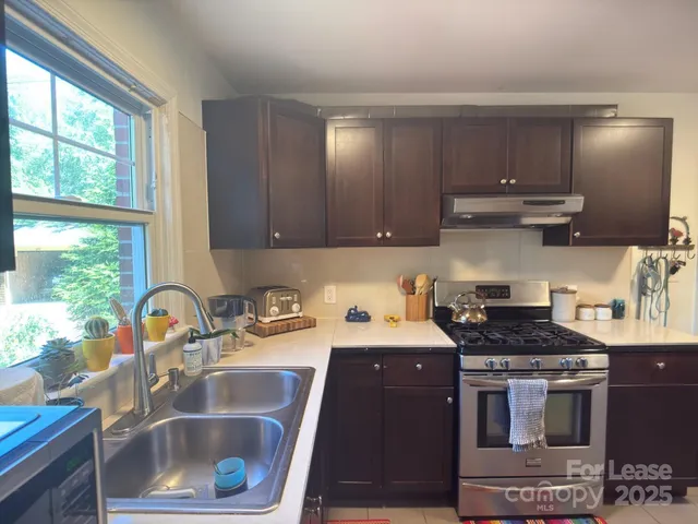 a kitchen with stainless steel appliances a sink a stove a microwave a sink and cabinets