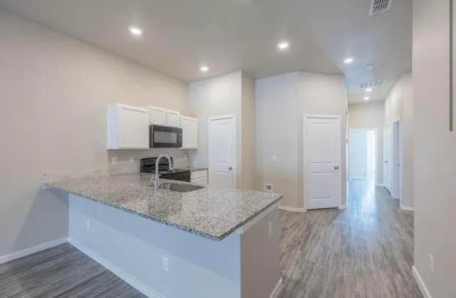 a kitchen with granite countertop kitchen island wooden floor center island stainless steel appliances and cabinets