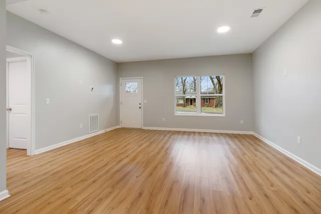 an empty room with wooden floor and windows
