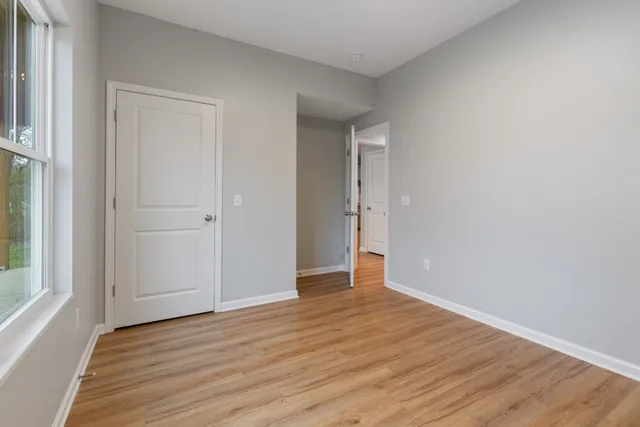 a view of an empty room with wooden floor and window