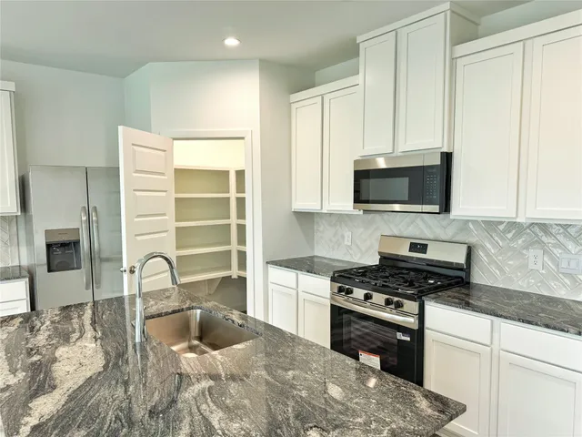 a kitchen with granite countertop a stove a sink and a microwave