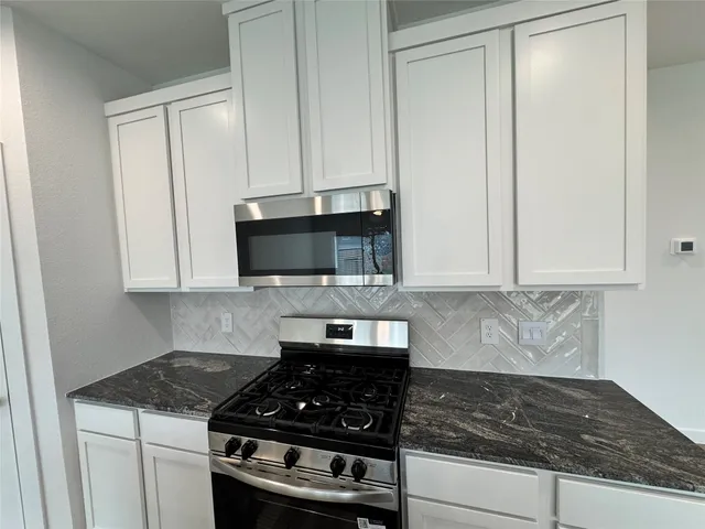 a kitchen with granite countertop stainless steel appliances a stove a microwave and cabinets