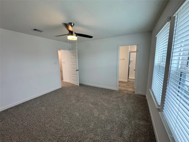 en empty room with windows and ceiling fan