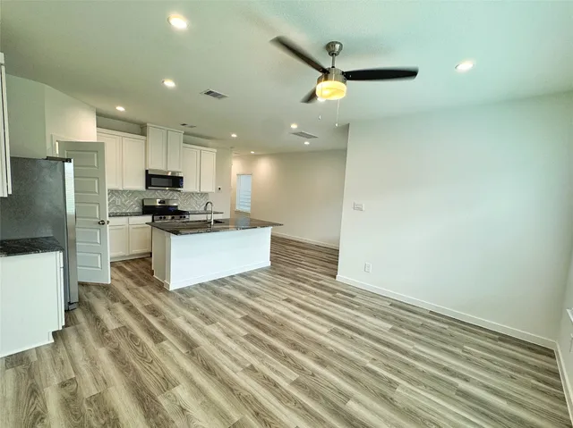 a kitchen with stainless steel appliances kitchen island a refrigerator sink and cabinets