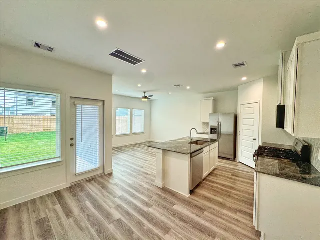 a large kitchen with stainless steel appliances kitchen island granite countertop a refrigerator and a stove top oven