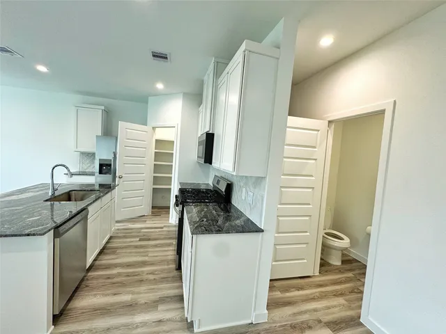 a kitchen with granite countertop a refrigerator and a sink