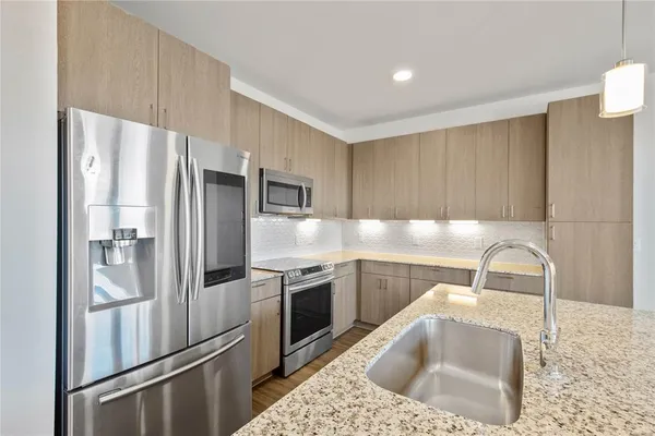 a kitchen with stainless steel appliances granite countertop a refrigerator sink and stove