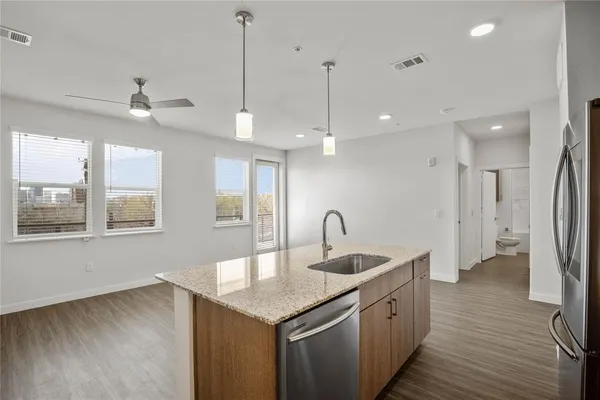 a kitchen with stainless steel appliances granite countertop a sink a refrigerator and a wooden floor