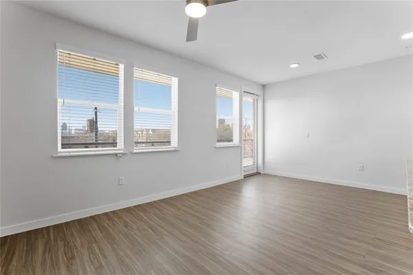a view of an empty room with wooden floor and a window