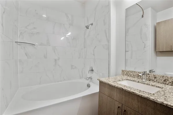 a bathroom with a granite countertop sink a mirror and a bathtub