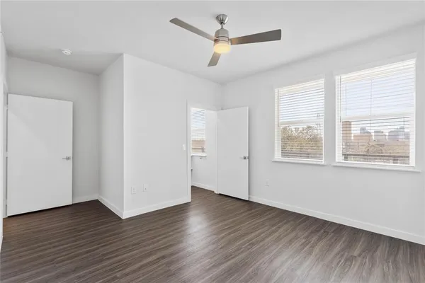 a view of empty room with wooden floor and fan