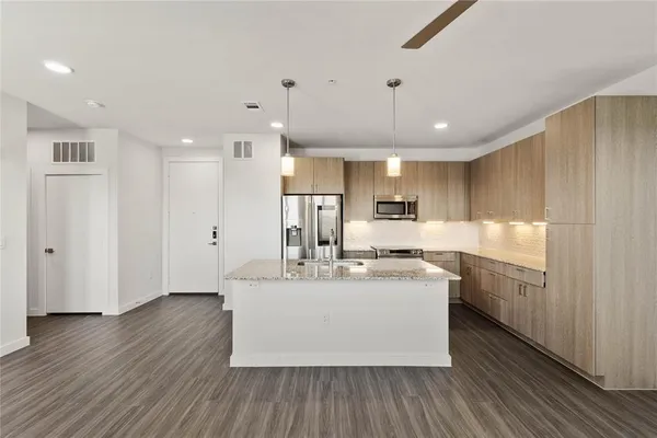 a large white kitchen with wooden floors and stainless steel appliances