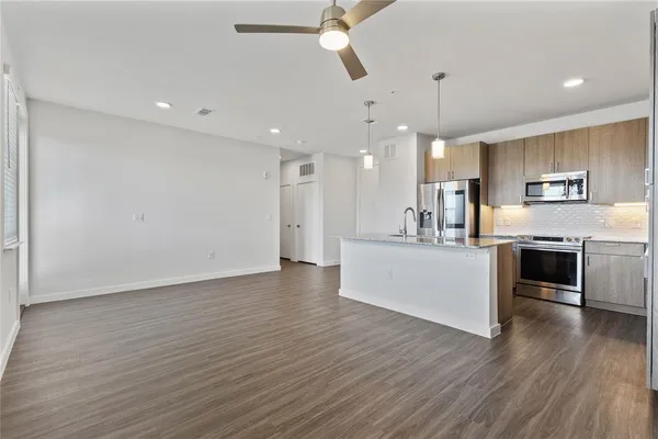 a view of kitchen with cabinets stainless steel appliances and wooden floor