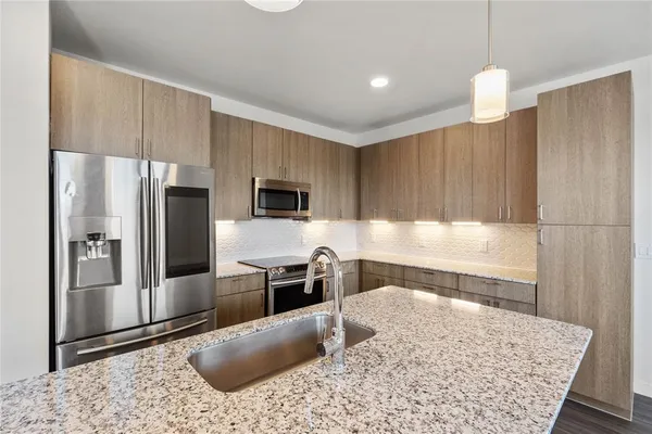 a kitchen with stainless steel appliances granite countertop a sink refrigerator and microwave