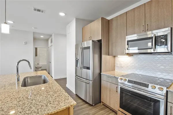 a kitchen with stainless steel appliances granite countertop a refrigerator a stove a sink and a microwave